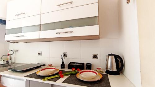 a kitchen with white cabinets and plates on a counter at Apartment Centar in Podgorica