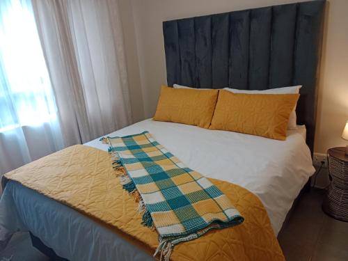 a bed with yellow pillows and a blanket on it at Mkhonto's waterfall ridge in Midrand