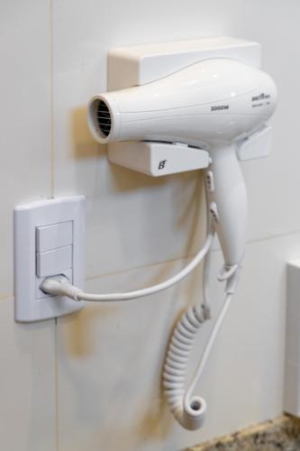 a white hair dryer hanging on a wall at Hotel Monsenhor in São Sebastião do Paraíso