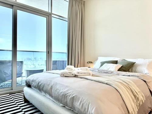 a bedroom with a large bed and a large window at Brand New Studio - Comfy & WFH in Dubai