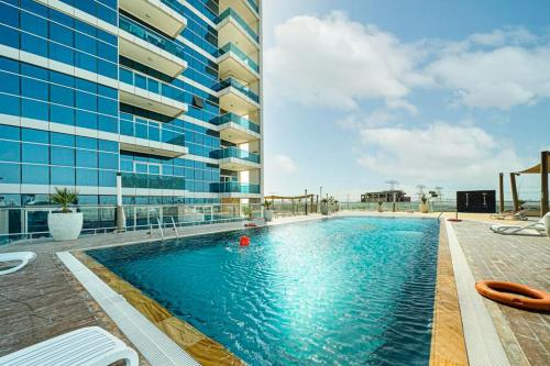 a large swimming pool next to a tall building at Brand New Studio - Comfy & WFH in Dubai