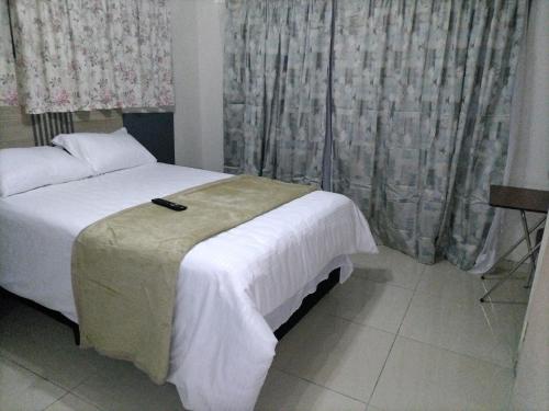 a hotel room with a bed and curtains at Willow's Guesthouse in Vereeniging