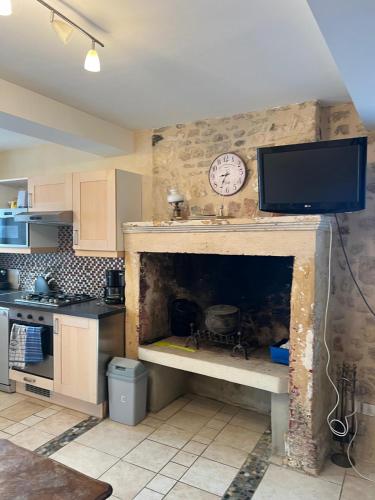 une cuisine avec cheminée et horloge. dans l'établissement Petite maison Vierville, à Vierville-sur-Mer