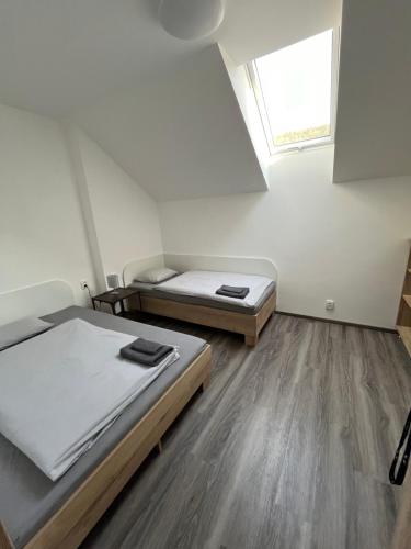 two beds in a small room with a window at Penzion Kopanský mlýn in Statenice
