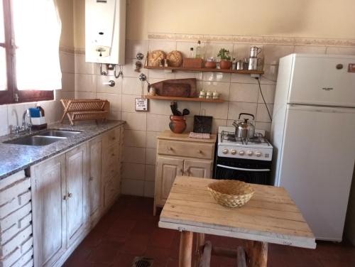 a kitchen with a table and a white refrigerator at Casona Inkill Huasi II in Tilcara