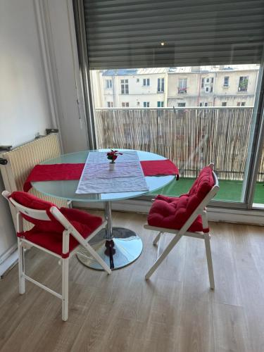 une table et deux chaises dans une pièce avec une fenêtre dans l'établissement appartement magnifique et confortable, à Paris