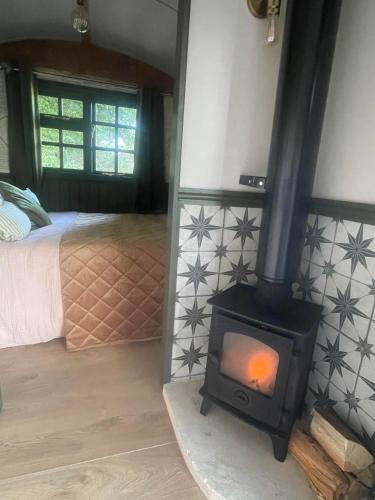 a wood stove in a bedroom with a bed at Shepherds Hut Farm Stay - The Nest in Mountfield