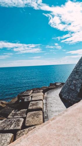 a stone pathway next to the ocean with a blue sky at Don Ignazio in Monopoli
