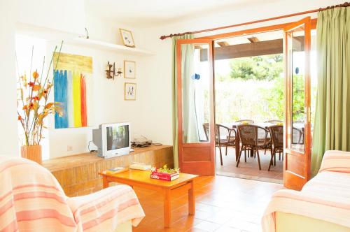 sala de estar con sofá, TV y mesa en Villa Solana en Portopetro