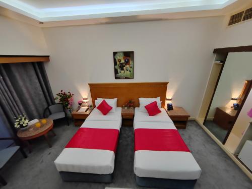 two beds in a hotel room with red pillows at Le Paradise Palace Hotel Deira Dubai Al Rigga in Dubai
