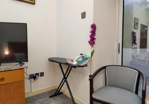 a table with a chair and a vase of purple flowers at Le Paradise Palace Hotel Deira Dubai Al Rigga in Dubai
