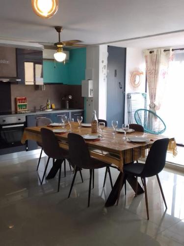 une table en bois dans une cuisine avec des chaises autour de celle-ci dans l'établissement Appartement chic et cosy, au Barcarès