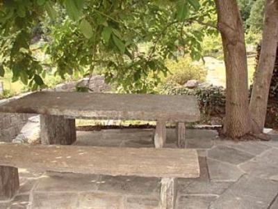 Rustico Al Noce في Riveo: كرسي خشبي جالس في حديقة فيها اشجار