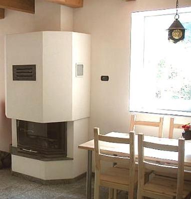 a kitchen with a fireplace and a table and chairs at Rustico Al Noce in Riveo