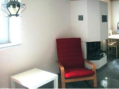una silla roja sentada en una sala de estar con una mesa en Rustico Al Noce, en Riveo