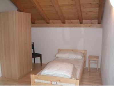 a small bedroom with a bed and a chair at Rustico Al Noce in Riveo