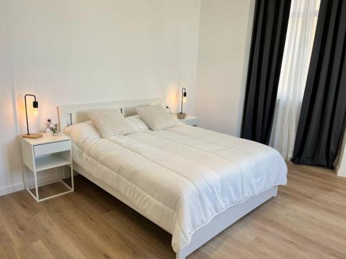 a white bedroom with a large bed and a table at Suites Larios Rooms in Málaga