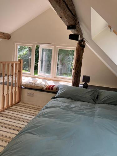 Un dormitorio con una cama en una habitación con ventanas. en Studio in medieval Welsh farmhouse, en Aber Cowarch