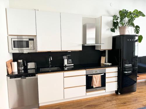 a kitchen with white cabinets and a black refrigerator at HAKANIEMI luxury apartment Helsinki center, 24h check in in Helsinki