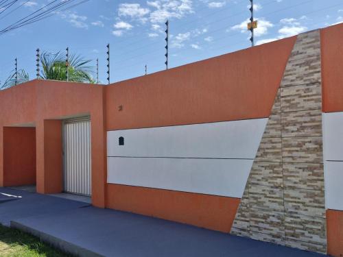 a garage with an orange and white wall at CASA de PRAIA NO FRANCÊS 3 QUARTOS SENDO 1 SUITE in Marechal Deodoro