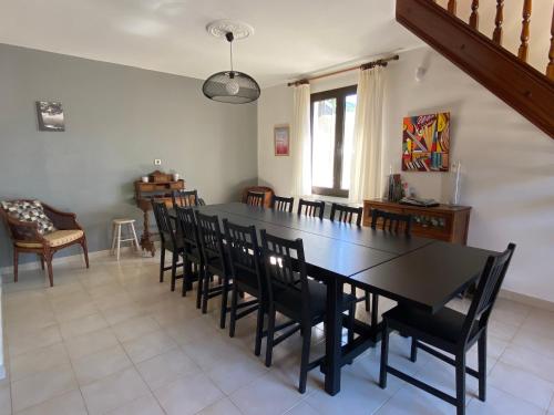 a dining room with a black table and chairs at Villa "les vacances" in Les Plans