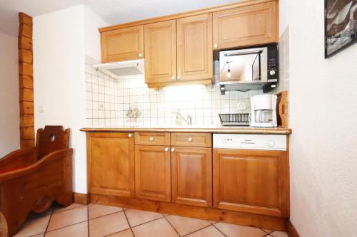- une cuisine avec des placards en bois et un four micro-ondes dans l'établissement Résidence Les Hauts De Chavants - Hauts de Chavants Berard 04 MAE-6426, aux Houches