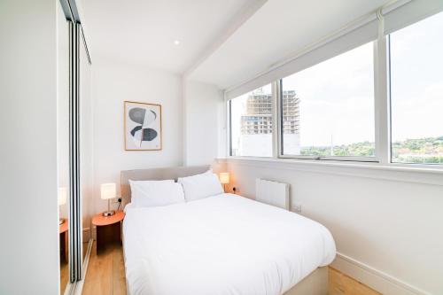 a bedroom with a white bed and a large window at Stylish Retreats on Olympic Way in London