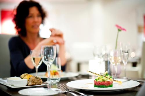 a woman sitting at a table with a plate of food at Sanadome Hotel & Spa Nijmegen in Nijmegen