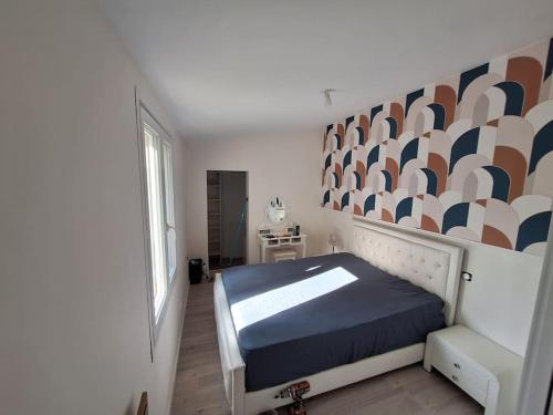 ein Schlafzimmer mit einem Bett und einer Wand mit einem Wandbild in der Unterkunft Belle maison au bord du plan d'eau in Saint-Jean-dʼAngély