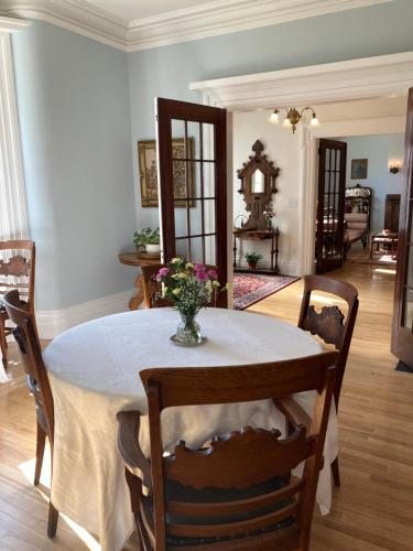 a dining room with a table with a vase of flowers on it at The Red House Fredericton in Fredericton