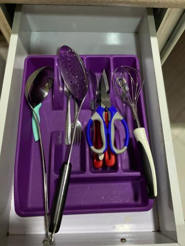 a purple plastic tray with utensils in a drawer at Hona Al Holm Furnished Units in Dammam