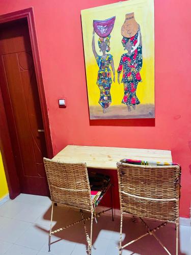 un tavolo e due sedie in una stanza con un dipinto di Chez Diogoye a Dakar