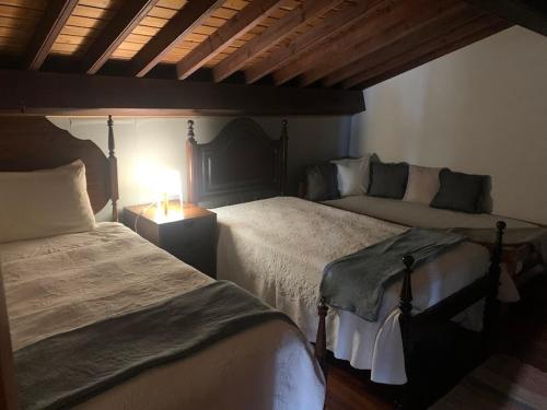 a bedroom with two beds and a table with a lamp at Sermar in Rabo de Peixe