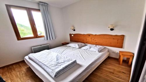 une chambre avec un grand lit avec une tête de lit en bois dans l'établissement Résidence Hameau Des Ecrins - HEA910 - APPARTEMENT 1 CHAMBRE + COIN MONTAGNE - TERRASSE VUE MONTAGNES MAE-2211, à Narreyroux