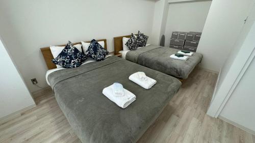 two beds in a small room with towels on them at JR Shin-Osaka 30s, Direct to Kansai Airport 關西空港直達,Shinkansen to Tokyo, Tokyo & Nagoya, Universal Studio 16 mins, Umeda 6 mins, Kyoto 25 mins, Early Check-In in Osaka
