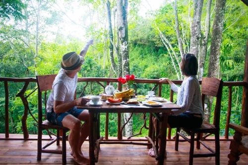 a man and woman sitting at a table on a deck at Ella Ecolodge in Ella