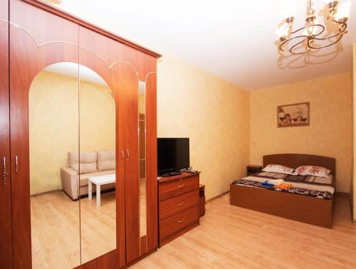 um quarto com uma cama, uma televisão e um espelho em ApartLux Kantemirovskaya em Moscovo