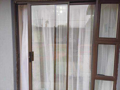 a glass door with white curtains in a room at Willow Guest house in Vereeniging