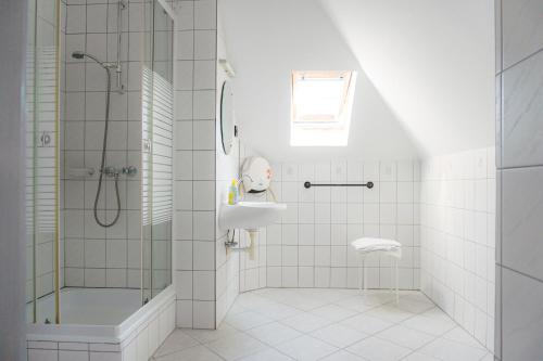 a white bathroom with a shower and a sink at Tea Apartman Balatongyörök in Balatongyörök