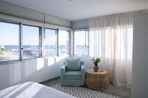 a bedroom with a bed and a chair and windows at La Posta Beach Hotel in Punta del Este