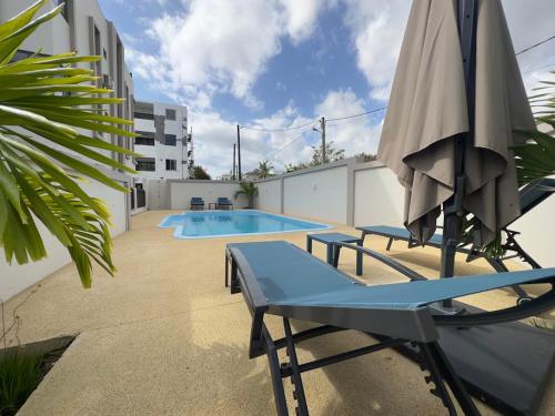 a swimming pool with an umbrella and two chairs and a table and an umbrella at SeaSand-Entire Luxury 3 BD condo - Close to beach in Flic-en-Flac
