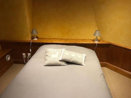 a bed with two pillows on it in a room at Ferme de Chenezeau - 15 personnes , 7 chambres in Gérardmer