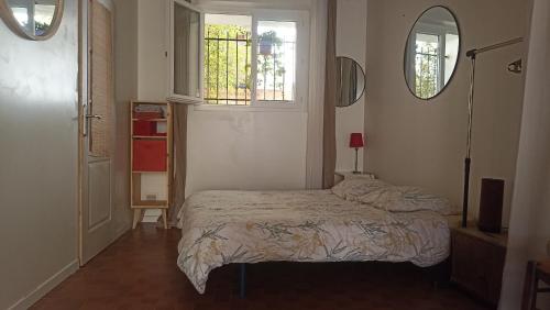ein kleines Schlafzimmer mit einem Bett und zwei Fenstern in der Unterkunft Studio privé - maison de village in Valensole