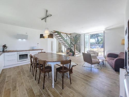 una cucina e una sala da pranzo con tavolo e sedie di Maison Bord de Plage avec Piscine, Sauna, Bains à Remous, Volley a Plouguerneau