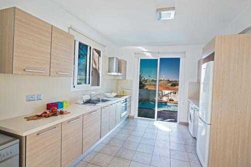 a kitchen with wooden cabinets and a view of the ocean at Seaspray Villa in Protaras