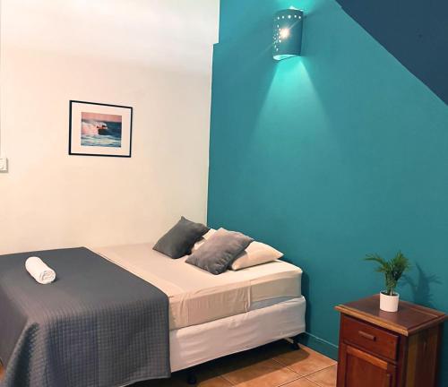 a bedroom with a bed with a blue wall at Point Break Santa Teresa in Santa Teresa Beach