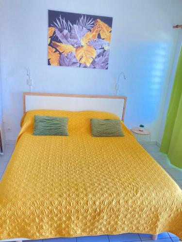 a yellow bed with two pillows in a bedroom at Studio Bougainvillier Style Bohème in Marigot