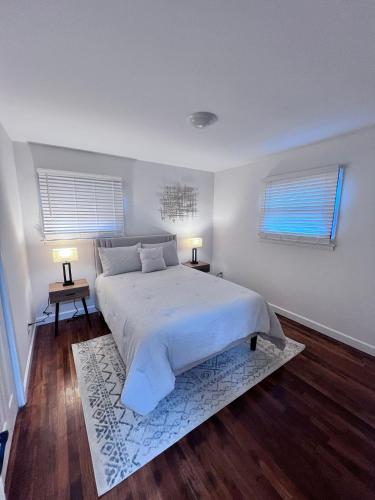 a white bedroom with a large bed and two windows at Comfortable 3BR Close to All in Dayton
