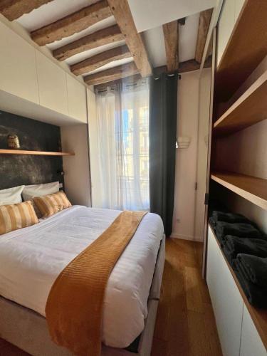 une chambre avec un grand lit et une grande fenêtre dans l'établissement Appartement à Saint-Paul en plein cœur du Marais 4 pers, à Paris