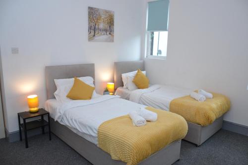 two beds in a hotel room with towels on them at Stylish Retreat near Birkenhead & Liverpool Your Cozy Home Away From Home in Wallasey